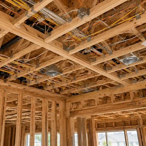 Exposed ceiling framing with professionally installed electrical wiring during the rough-in phase of new residential construction